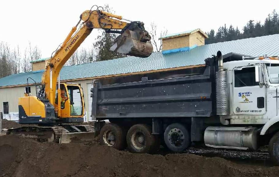 Swick and Son Excavator and dump truck hauling debris 